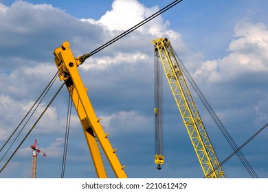 Heavy Floating Steel Crane And Boom. Bridge Construction Closeup. Lifting And Hoisting Device. Isolated Industrial Machine Part. Twisted Steel Cables And Hooks. Blue Sky And White Clouds.