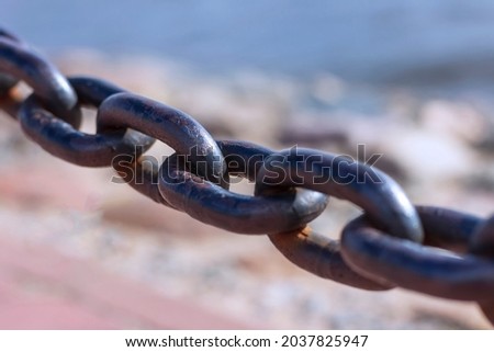 Heavy forged chain on the fence of the Neva embankment. The links of an old chain, illuminated by the sun, close-up.