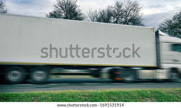Heavy goods vehicle on highway. Car is blurred\
to make it impossible to identify brand of machine and to give\
dynamics to image. Concept of modern operative, prompt delivery of\
goods, trucking