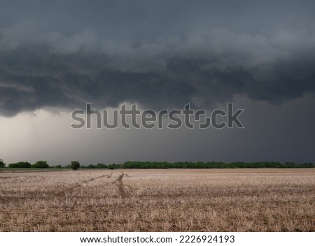 Heavy, gray storm clouds hanging over a stubble field with cut, dried grain stalks. Photographed in Oklahoma. Image has copy space.