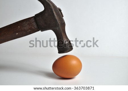 Heavy hammer on the way to crash an egg. Conceptual themes