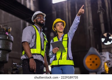 Ingenieros de la industria pesada que trabajan en la ingeniería de la fábrica de metal de acero, ingeniero técnico caucásico superior asesora a una trabajadora asiática especialista en industria en la zona de construcción.
