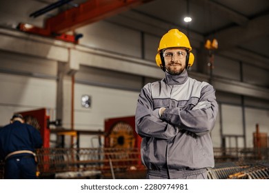 A heavy industry and metallurgy worker in protective uniform is proudly standing in facility and smiling at the camera. - Shutterstock ID 2280974981