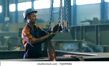 Heavy industry worker at a factory is working with hooks from a crane. - Powered by Shutterstock