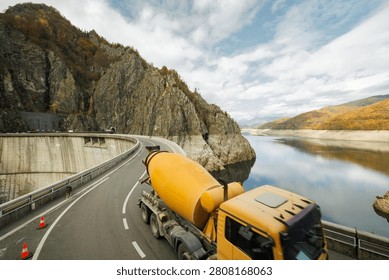 Heavy machinery operates efficiently as the controlled emptying of Vidraru dam unfolds against a backdrop of vibrant autumn foliage.