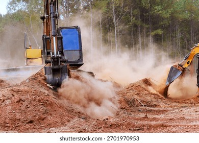 Heavy machines work to clear plot of land, creating dust clouds in forest landscape an active construction area