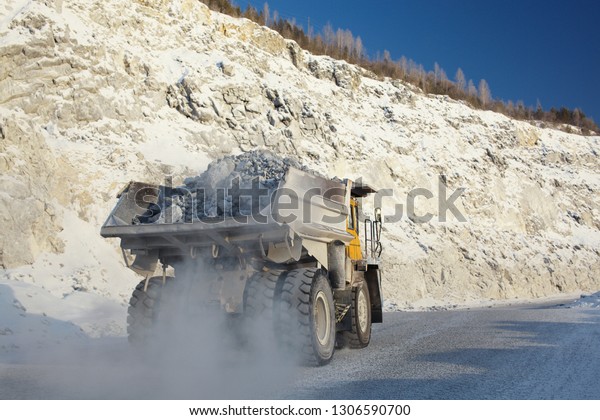 Heavy mining dump\
truck transports ore stone in the quarry mining enterprise,\
close-up. Mining\
industry.
