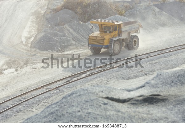Heavy mining truck transports\
crushed stone along a road in a stone quarry. Mining\
industry.