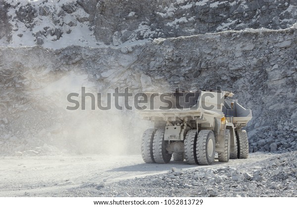 Heavy mining trucks stand in a dusty quarry in\
sunny weather close-up, rear view. Mining industry. Quarry mining\
equipment.