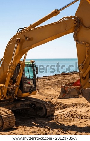 Heavy modern yellow digger excavator on the beach