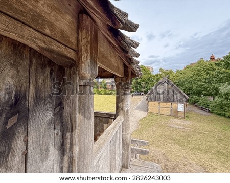 The heavy oak beams of the gate tower frame a reconstructed wattle-and-daub Viking house inside the ring fortress of Trelleborgen in Trelleborg, Sweden.