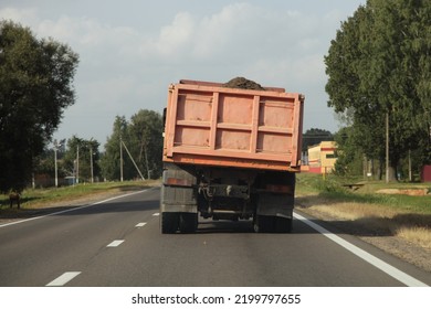 Heavy Overloaded Curvy Dumper Truck Drive With Bulk Cargo On A European Countryside Asphalt Road At Summer Day