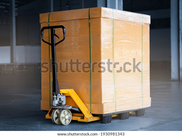 Heavy Package Box\
Wrapped Plastic Film on Pallet with Hand pallet Truck. Cargo\
Shipment. Shipping\
Warehouse.