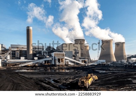 A heavy plant machine scraping coal from a fossil fuel stack at a large coal fired power station to burn for non-renewable electricity generation