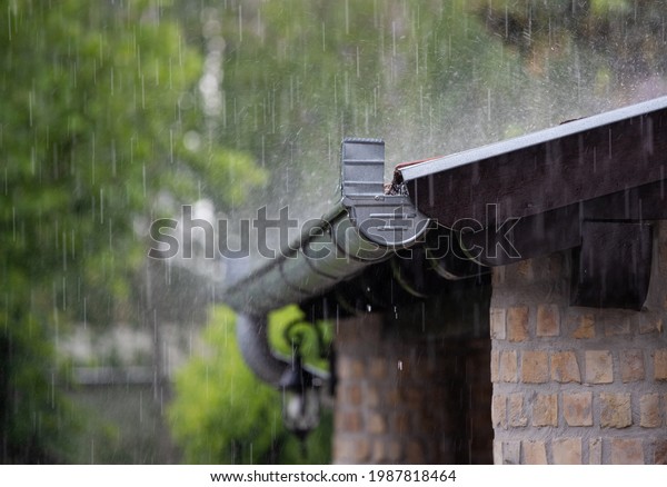 Heavy rain falling on the roof and metal gutter of\
brick house in summer\
season