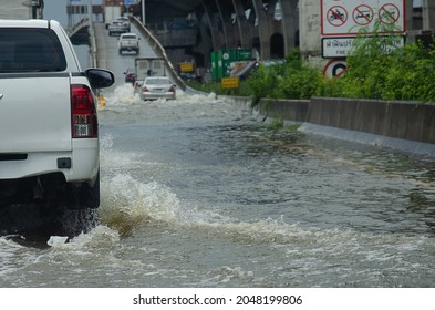 Heavy rain floods the roads of Thailand. The car runs through the flooded water.