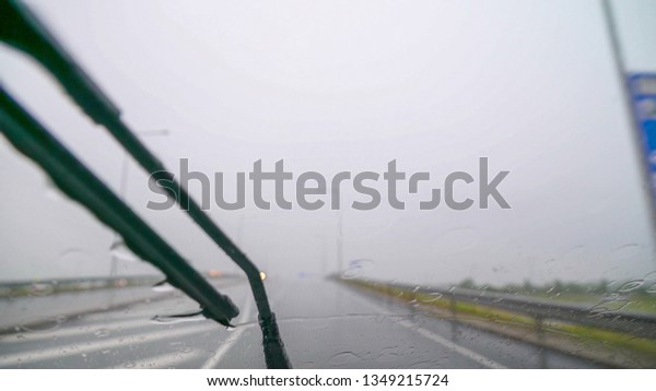 Heavy rain pouring\
outside while on the road as seen on the cars dash camera and the\
wipers on the front