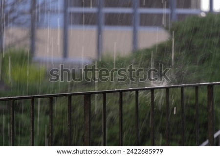 Heavy rain pours on the railing with splash