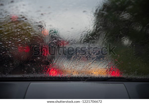 Heavy rain. Raindrop on the window car. Abstract\
blur bokeh of traffic and car light. poor view caused by heavy rain\
and back light.