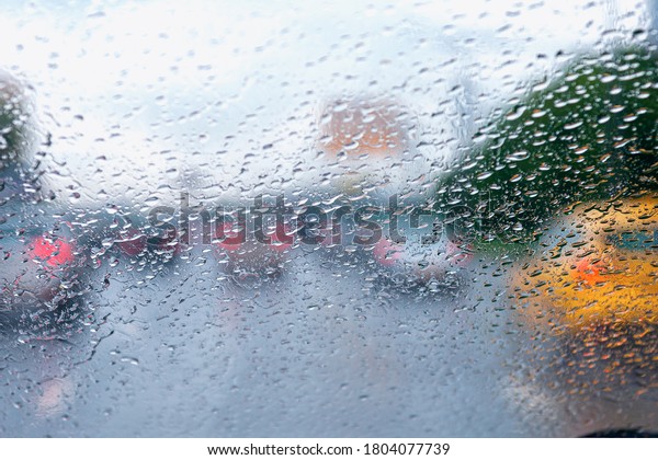 Heavy rain, raindrops on the windshield, blurred\
cloudy background from a car window. Raindrops on a windshield in\
rainy weather.