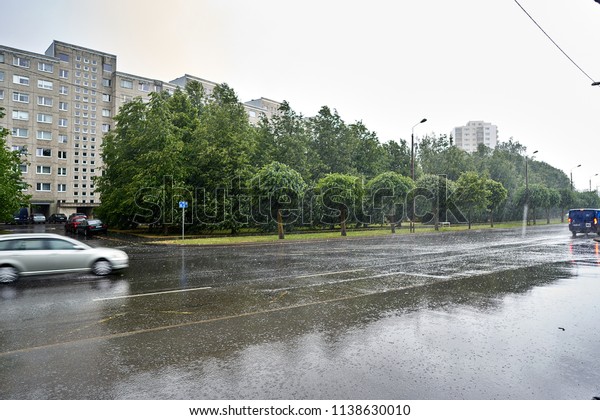 Heavy rain with wind on city street with\
apartments and cars as\
background.
