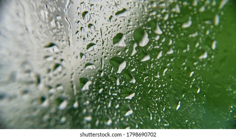 Heavy Rainfall / Raindrops On A Window Looking Out To A Mostly Green Garden