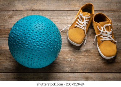 Heavy Rubber Slam Ball Filled With Sand On A Rustic Wooden Deck With Minimalist Barefoot Sneakers, Exercise And Fitness Concept