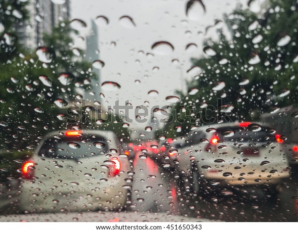 Heavy rush hour traffic\
view through windshield with rain drops, Driving in the rain,\
Bangkok,Thailand.