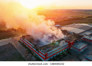 Heavy smoke in burning industrial distribution warehouse or storehouse industrial hangar from burned roof, aerial view of fire disaster