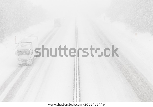 Heavy\
snowfall on the highway. Dangerous winter weather with low\
visibility. White cargo truck on the\
freeway.