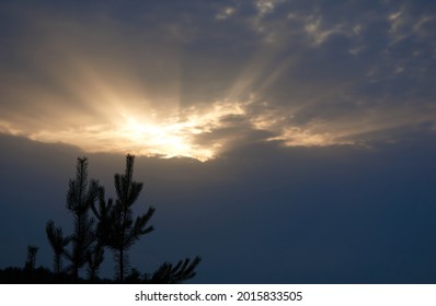 Heavy stormy dark rainy sky with cloud with sun illuminated hole over the field and forest silhouette on a summer evening, beautiful natural landscape. High quality photo - Powered by Shutterstock