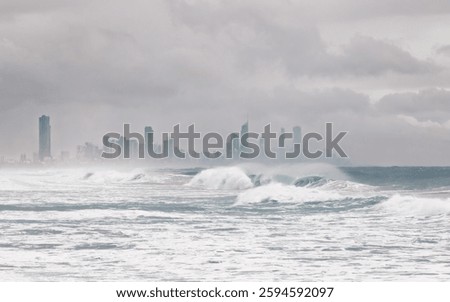 Heavy surf with breaking waves with wind spray and threatening skies with Surfers Paradise in the background as the edge of cyclone Alfred touches on the Gold Coast in Queensland, Australia.
