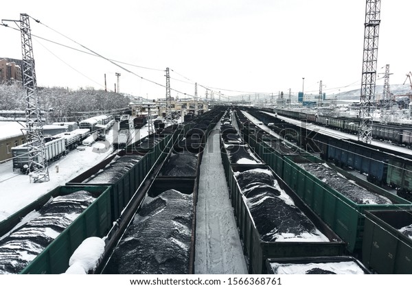 heavy train with\
dirty wagons with coal stands at the station under the bridge on a\
cloudy frosty day in\
winter