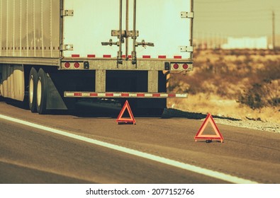 Heavy Transportation Theme. Broken Semi Truck on Side of a Highway Trailer Close Up and Warning Triangles. Roadside Asssitance.