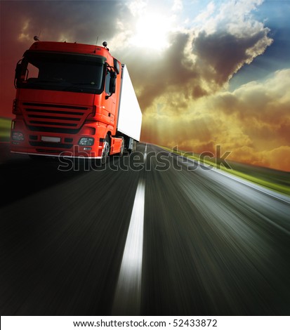 Heavy truck on blurry asphalt road under sunlight