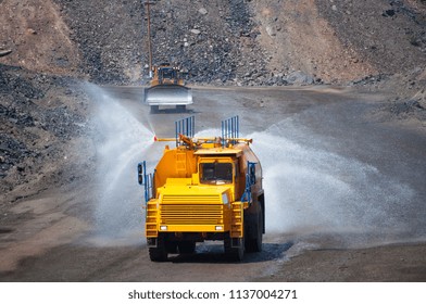 Heavy truck pours the road with water in the iron ore quarry. Dust removal, protection of the environment. Irrigation of the road from dust - Shutterstock ID 1137004271