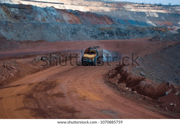 Heavy truck pours the road with water in the iron\
ore quarry. Dust removal, protection of the environment. Irrigation\
of the road from dust