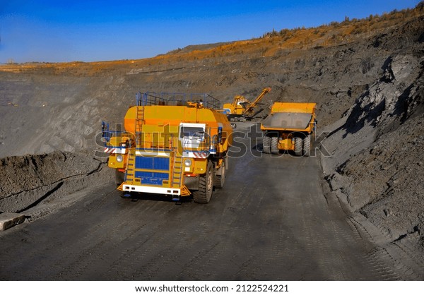 Heavy truck pours the road with water in the iron\
ore quarry. Dust removal, protection of the environment. Irrigation\
of the road from dust.