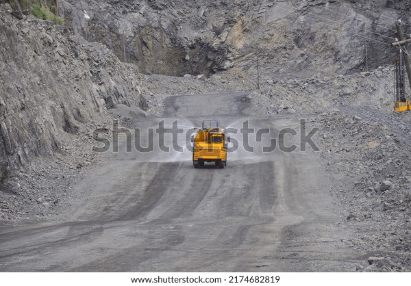 Heavy truck pours the road with water in the iron\
ore quarry. Dust removal, protection of the environment. Irrigation\
of the road from dust	