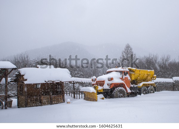 Heavy truck under\
snow during a snowfall.