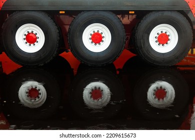 Heavy Truck Wheels With White Rims And A Red Center, Standing In A Puddle With Reflection In The Water.