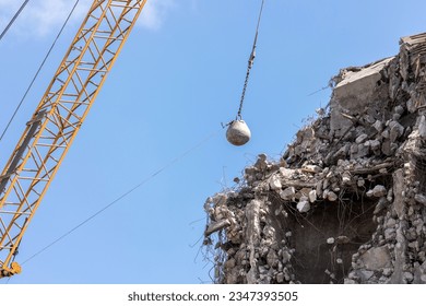 Heavy wrecking ball crane demolishing old building against blue sky in Magdeburg Germany. Building dismantling and construction waste disposal recycling service