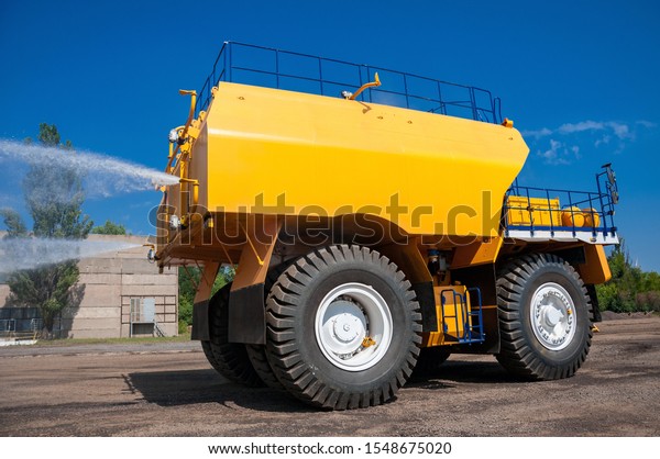 heavy yellow irrigating machine watering ground at\
sunny cloudless day