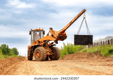 A heavy-duty construction vehicle or forklift driving along a dusty dirt road, stirring up clouds of dust as it moves forward.
