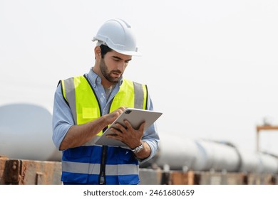 Heavy-duty industrial engineers stand in a pipeline manufacturing facility using digital tablet computers for the construction of products to transport oil, gas and fuel. - Powered by Shutterstock