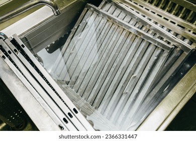 Heavy-duty sink containing multiple filters from industrial-grade hoods, immersed in a solution specifically designed for deep cleaning and degreasing - Shutterstock ID 2366331447