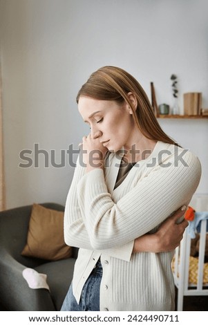 heavy-hearted and withdrawn young woman standing in nursery room at home, grieving and frustration