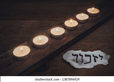 Hebrew inscription "remember" on a piece of paper and Six candles