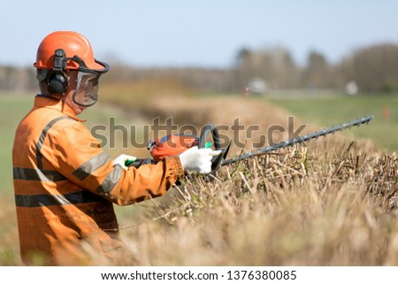 Similar – Image, Stock Photo Gardener trimming a hedgerow using a hedge trimmer in the garden of a customer with earmuffs on for protection