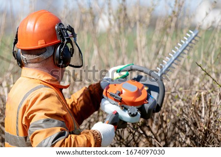 Similar – Image, Stock Photo Gardener trimming a hedgerow using a hedge trimmer in the garden of a customer with earmuffs on for protection